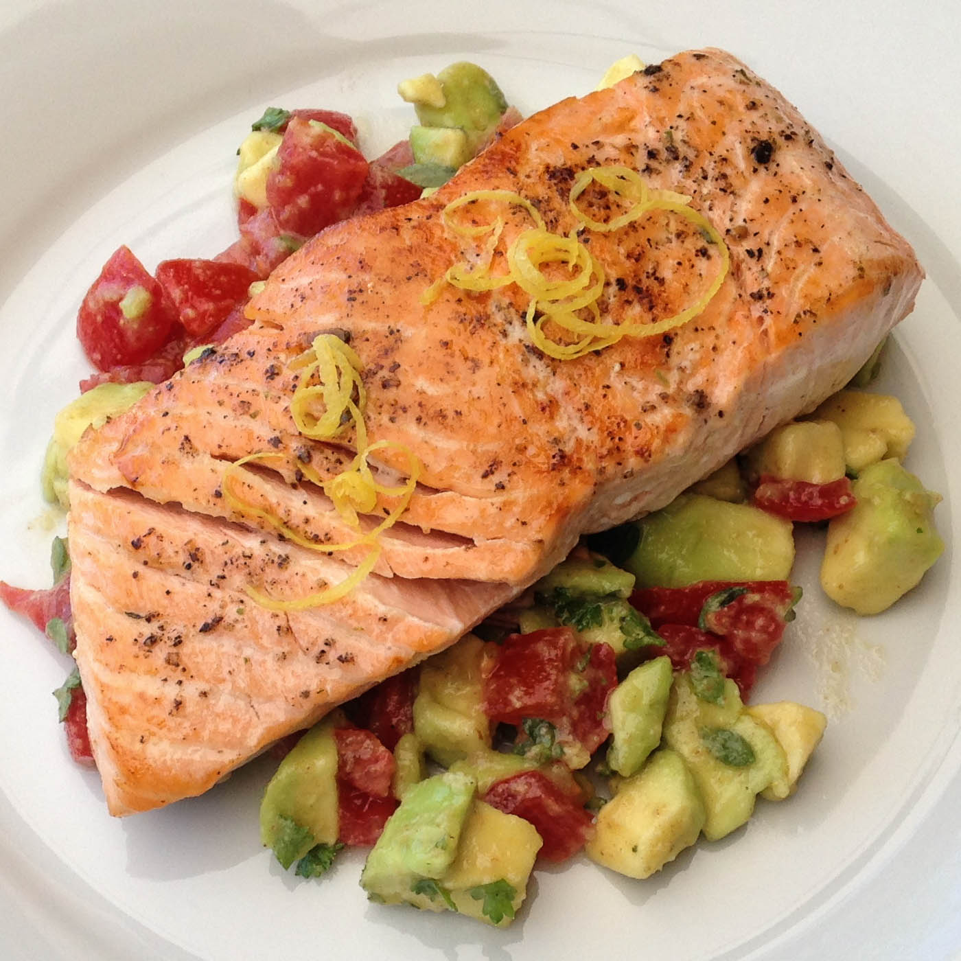 Kochdiele: Gebratener Lachs auf einem Avocado-Tomatenbeet